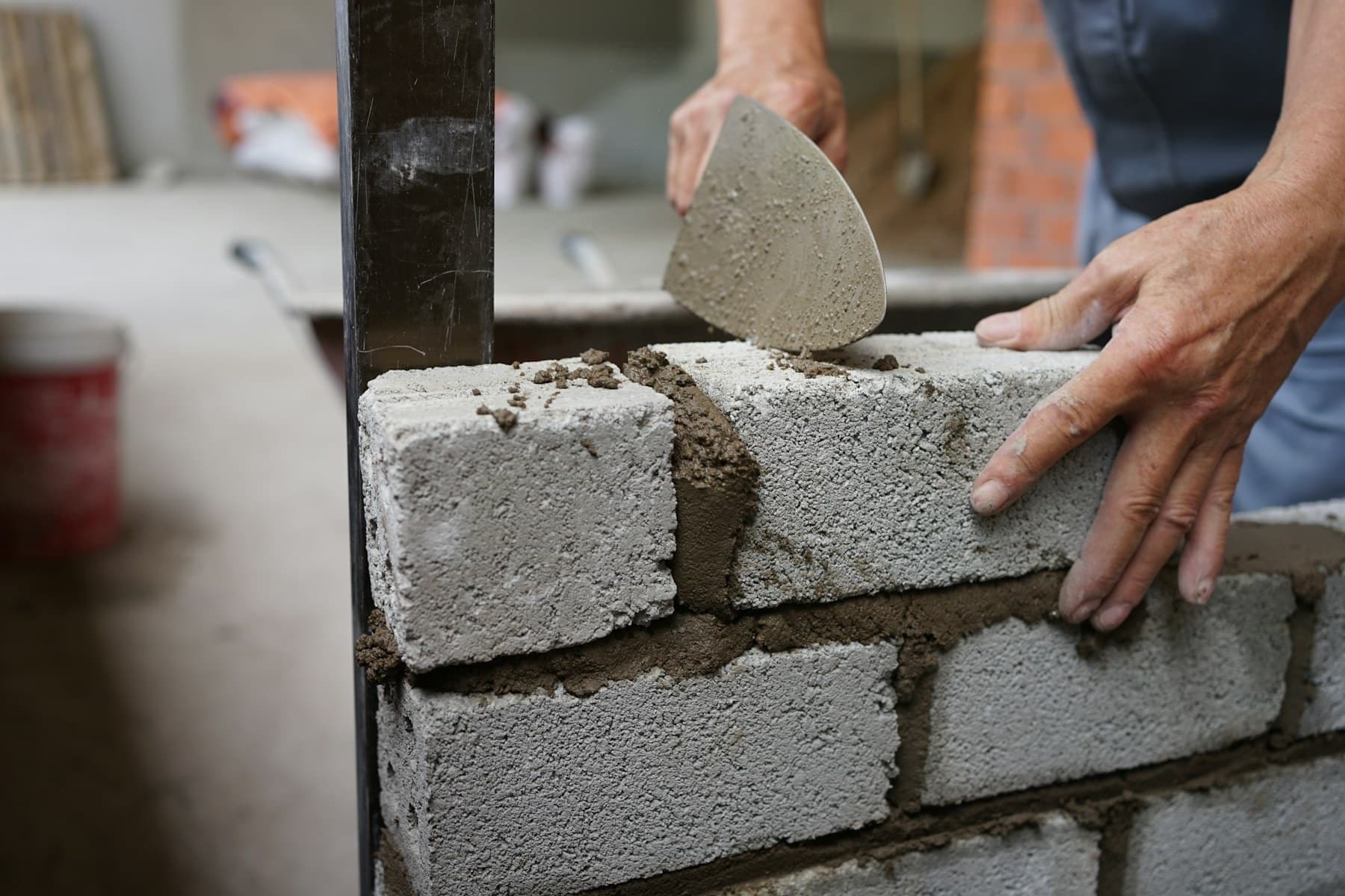 Mason laying cinder blocks with a trowel and fresh mortar