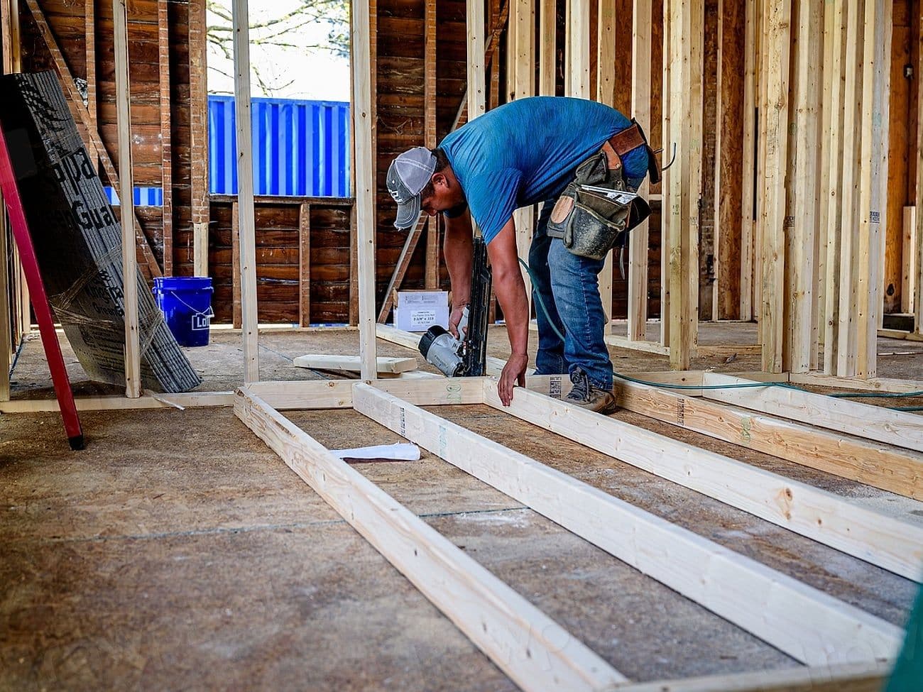 Carpenter framing an ADU with lumber laid across the subfloor