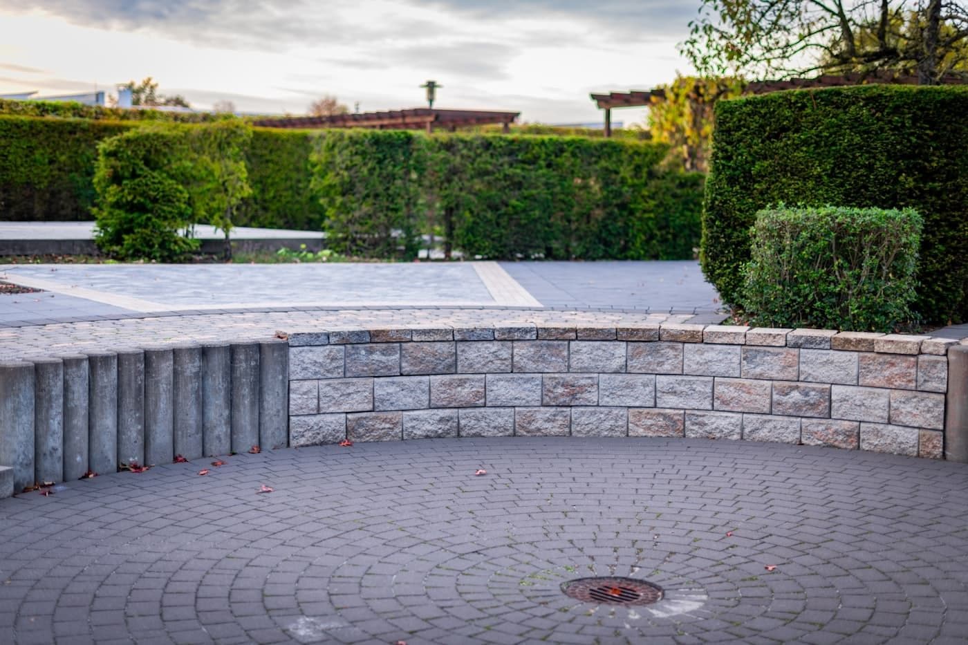 Curved block retaining wall around a paver patio at dusk