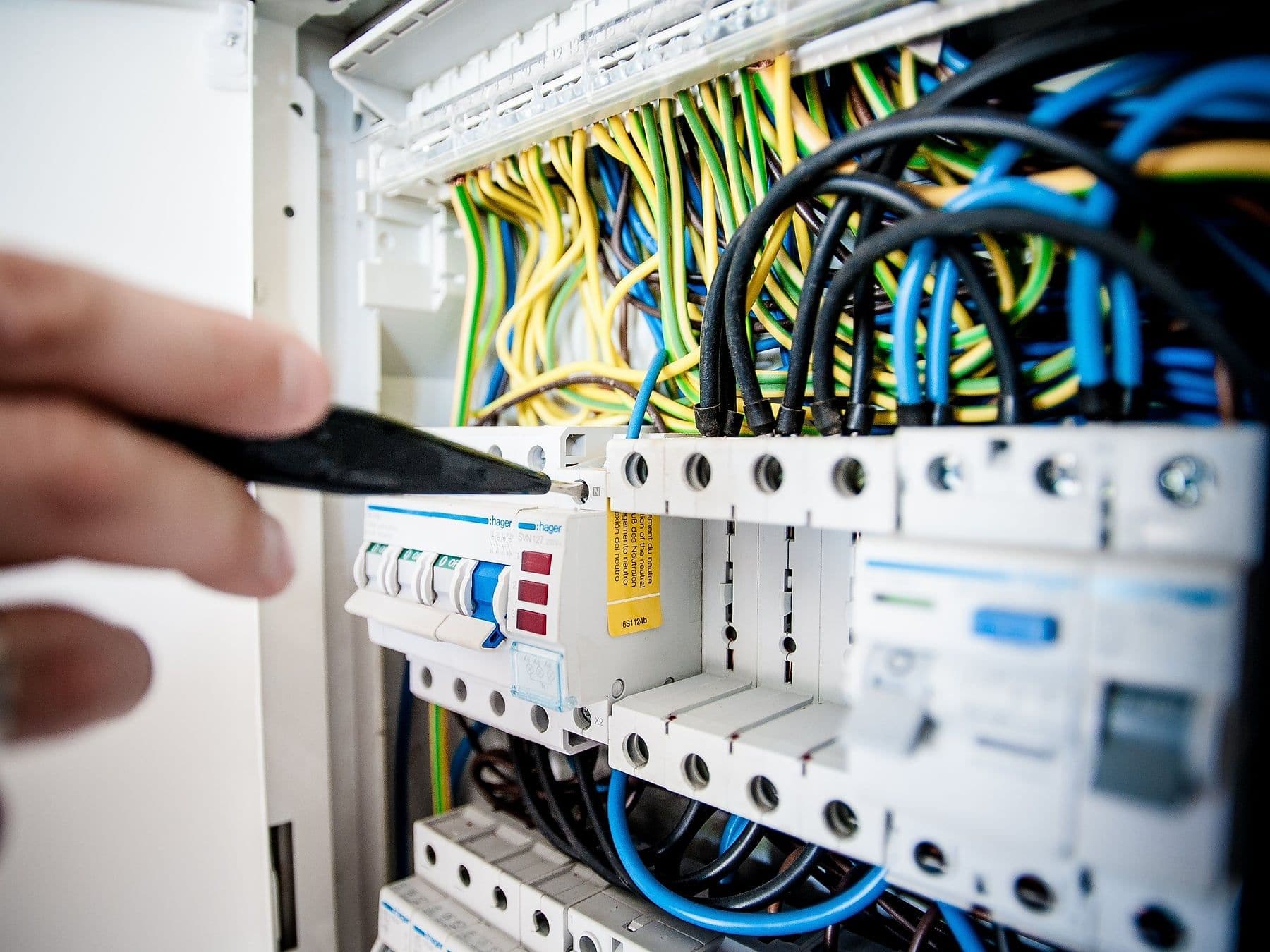 Electrician working inside a residential breaker panel with colour-coded wiring