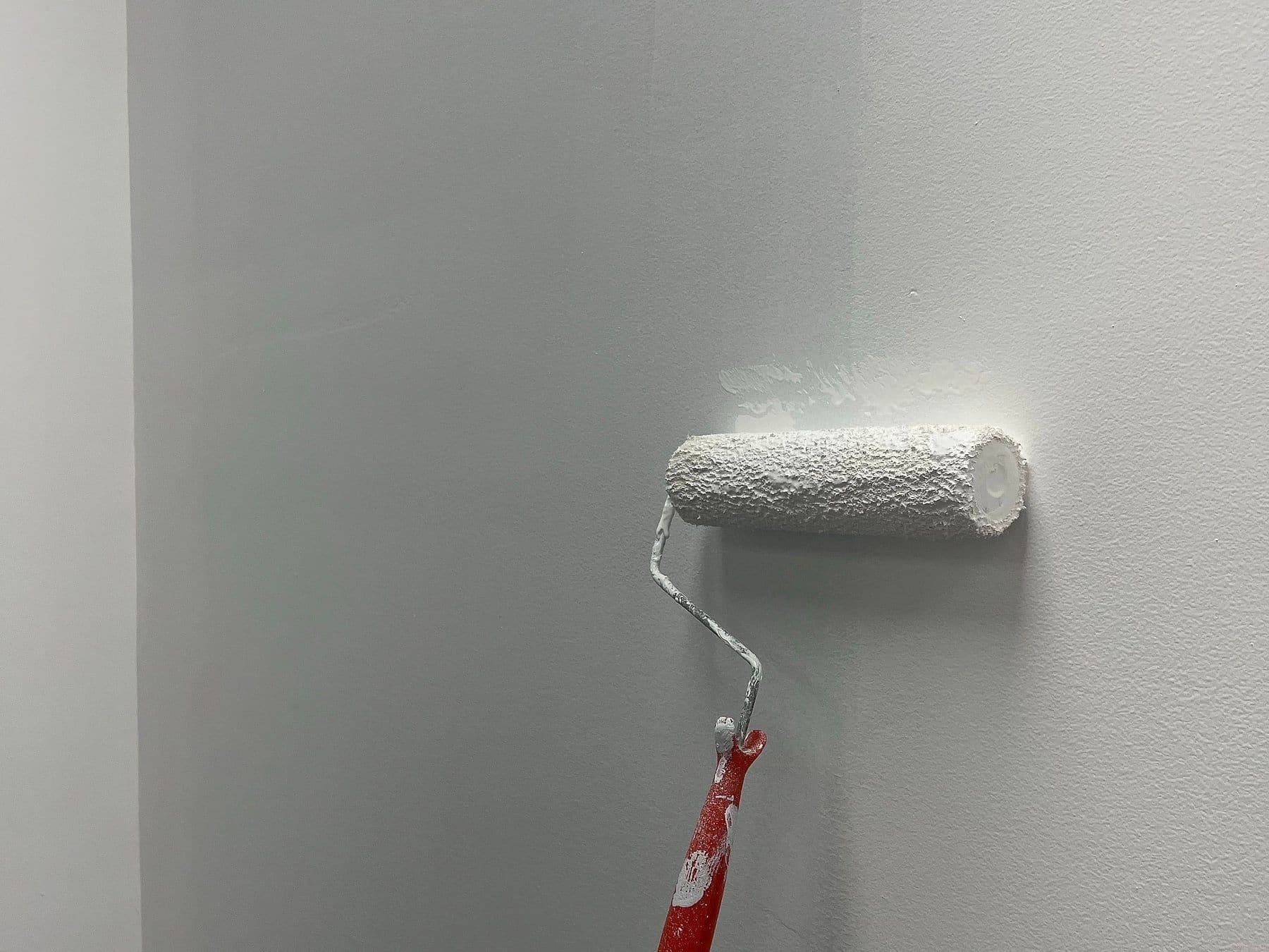Paint roller applying a white coat to an interior wall
